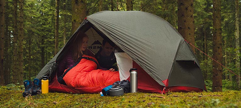 woman in tent pitched in woodland